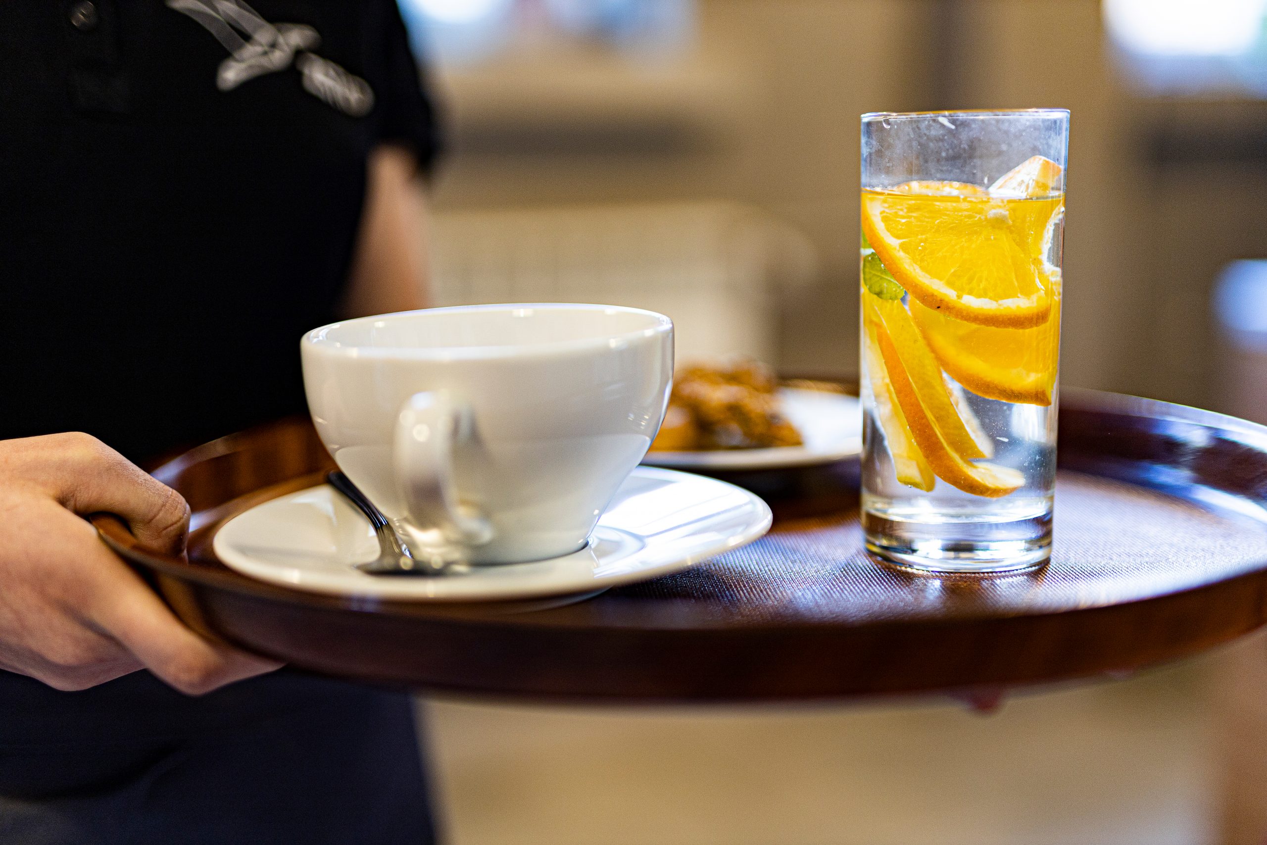 na tacy filiżanka i szklanka z wodą z cytrusami