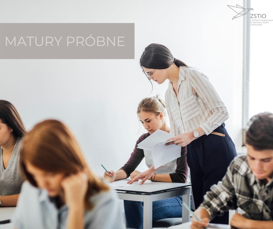 zajęcia szkolne, uczniowie siedzą przy ławkach, nauczyciel rozdaje kartki