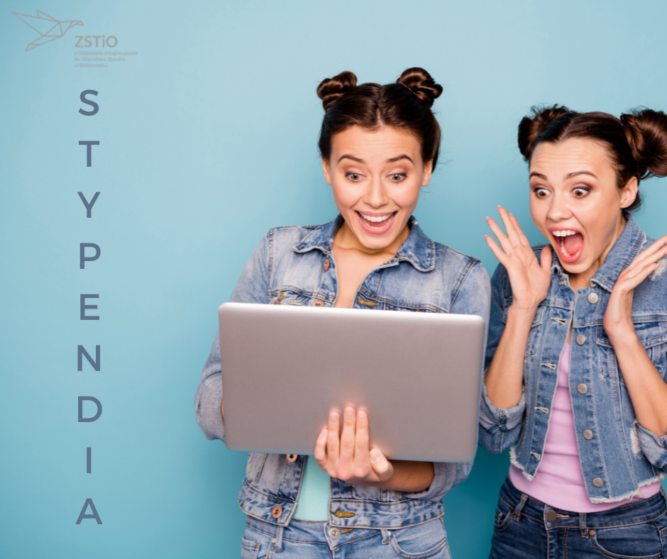 Niebieskie tło, dwie młode kobiety, jedna z nich czyta laptop, mają zdziwione miny