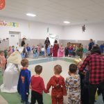 grupa dzieci i dorosłych tańczy w kole, trzymają sie za ręce