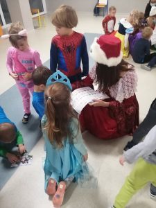 na podłodze siedzą dzieci, dziewczyna przebrana w strój historyczny rozdaje naklejki