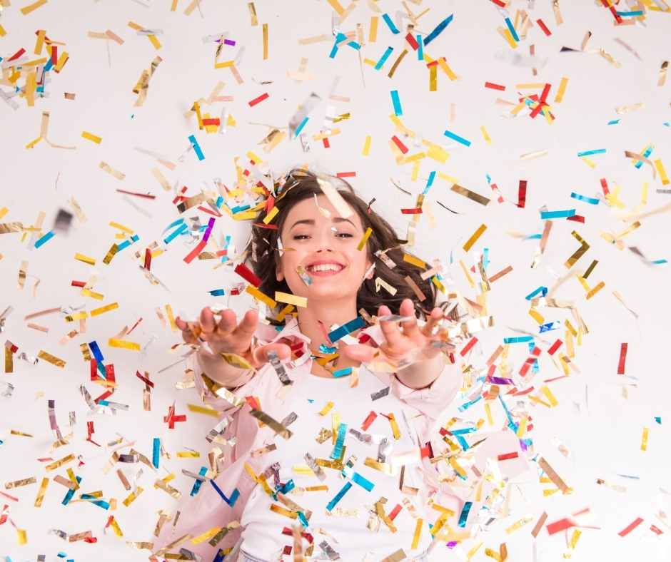 młoda kobieta na pastelowym tle , leży i sypie się na nią konfetti