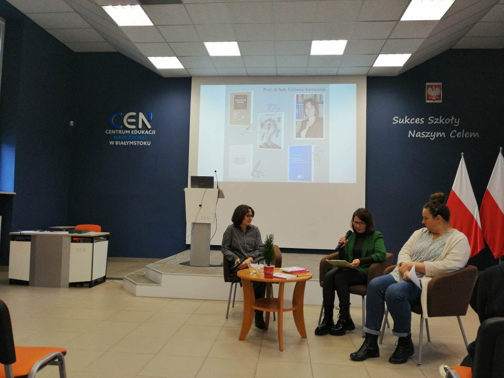 trzy kobiety siedzą na fotelach, jedna z mokrofonem, w tle prezentacja