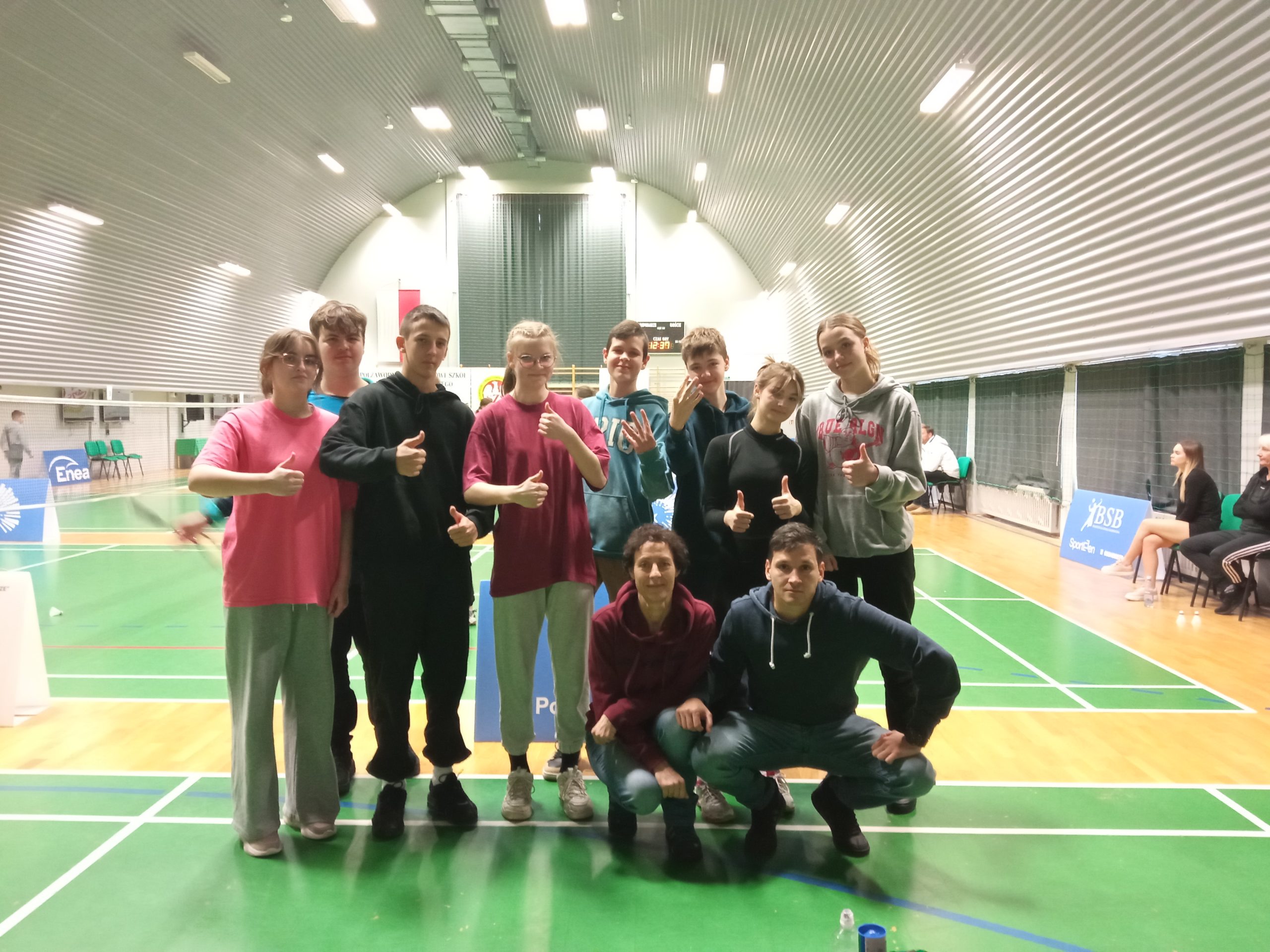 grupa dziewczyn i chłopców pozuje do zdjecia, stroje sportowe, w tle hala sportowa