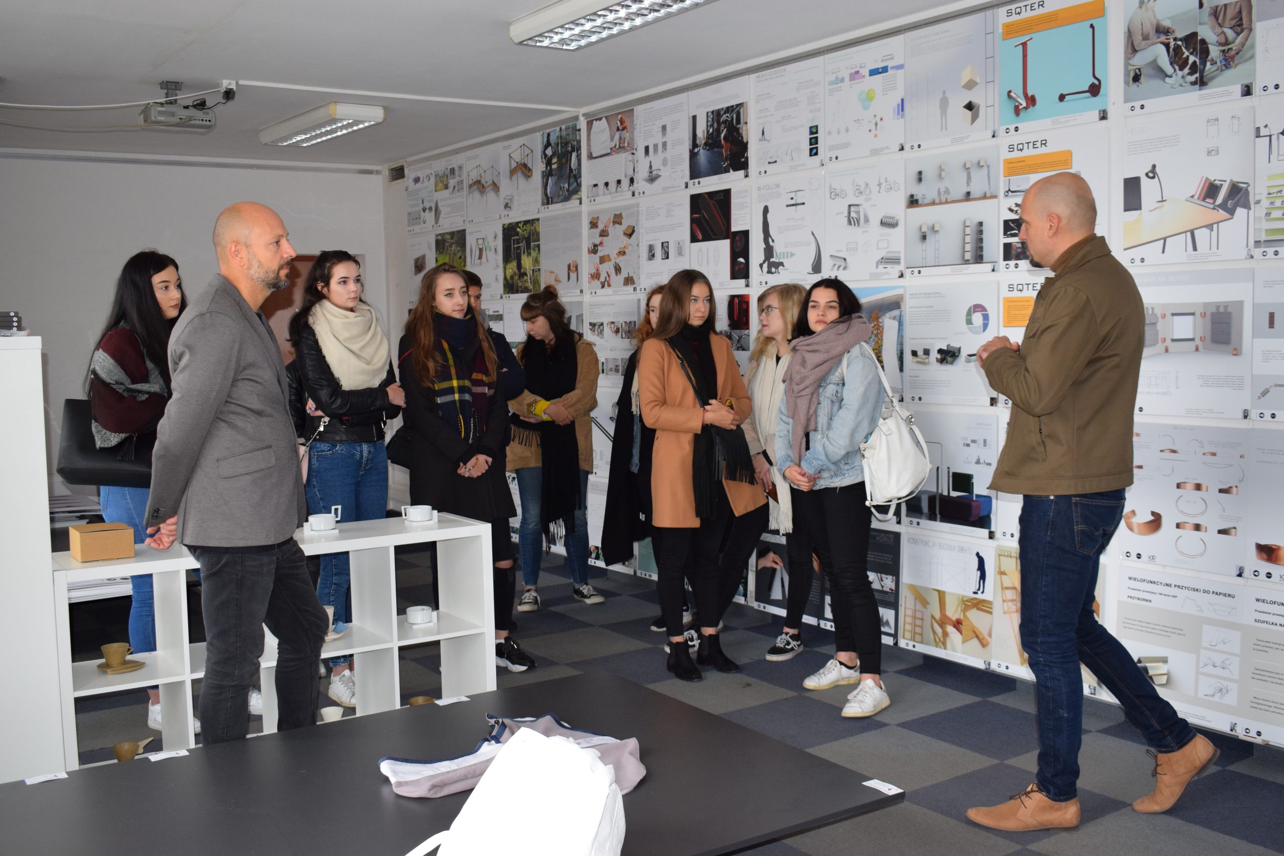 grupa ludzi na tle ściany z wydrukami