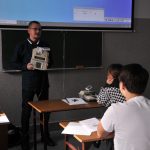 nauczyciel z urządzeniem elektronicznym na tle tablicy