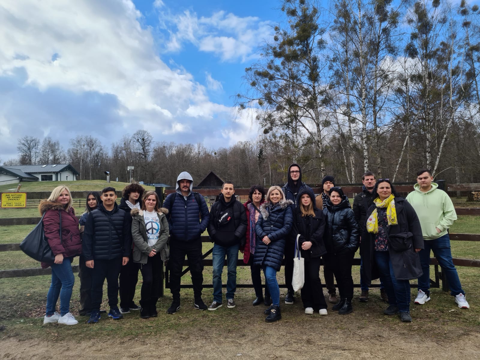 grupa ludzi, kobiety i mężczyźni stoją na tle drzew