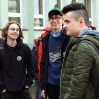 3 uczniów stoi na podwórku