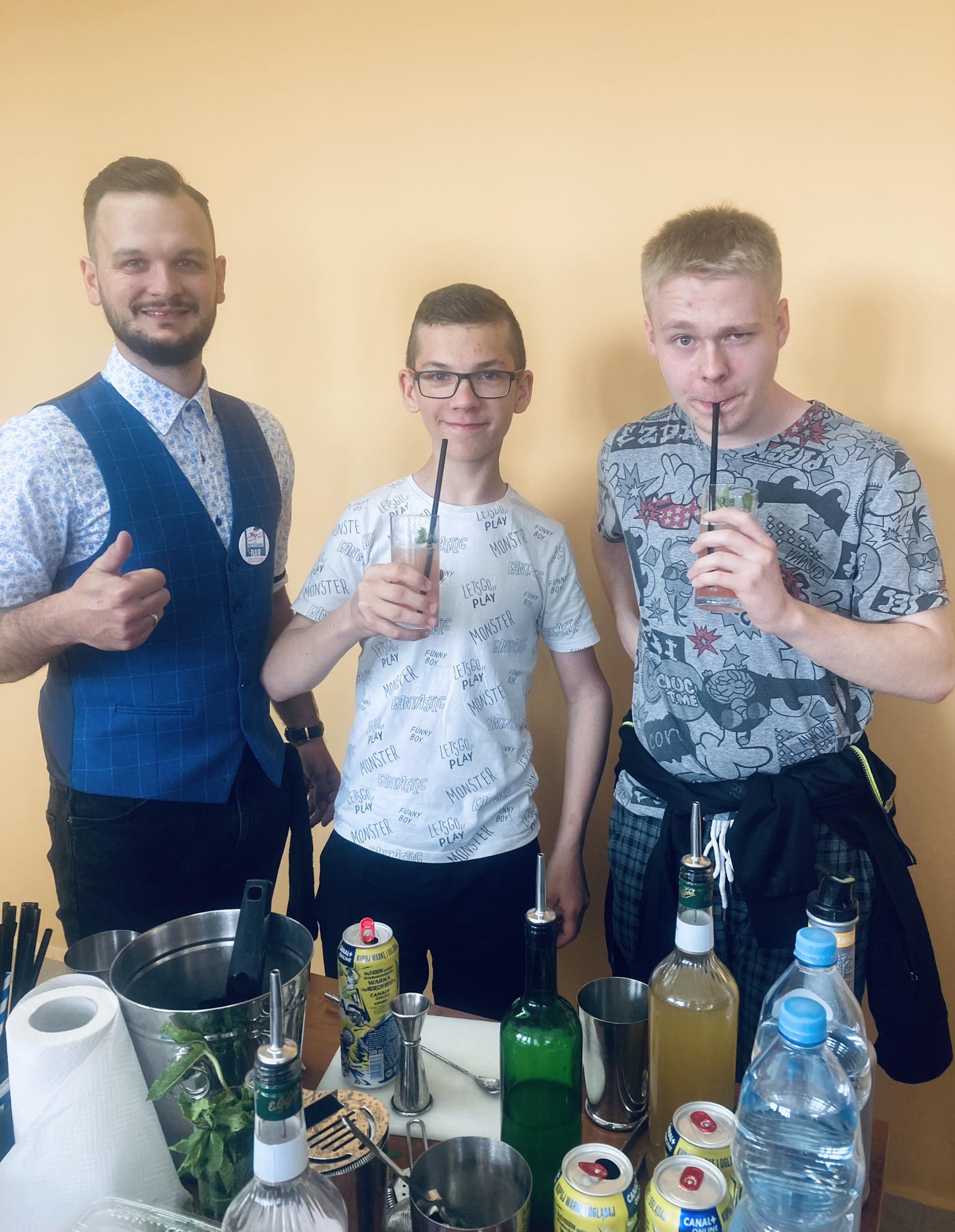 trzech mężczyzn pozuje do zdjęcia, dwóch ma szklanki z napojem ze słomkami